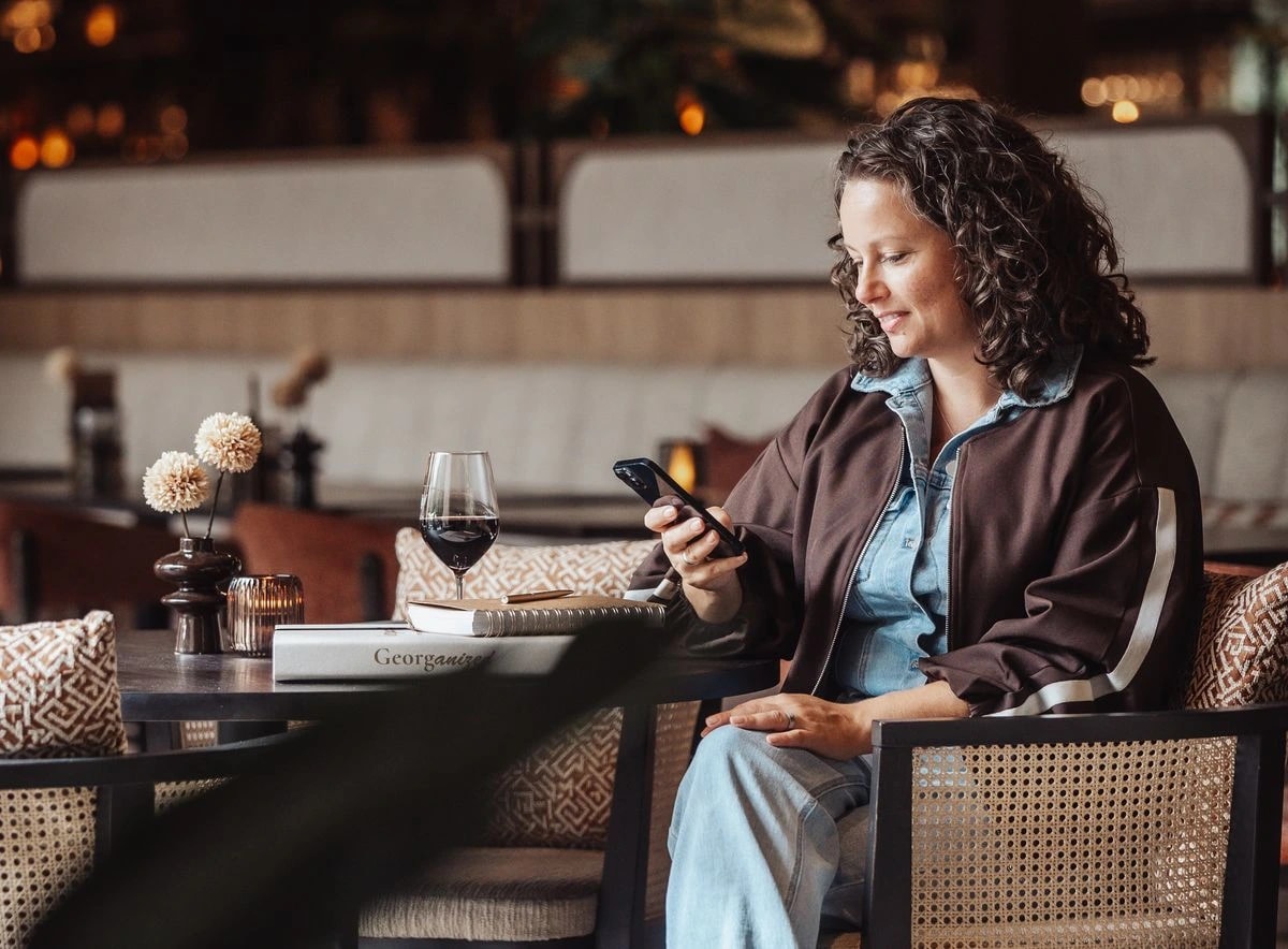 Georget bekijkt haar telefoon aan een tafel in een restaurant