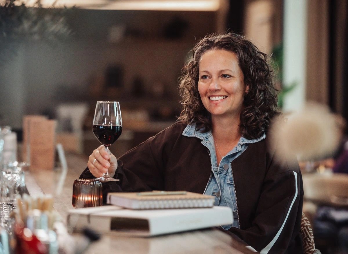 Georget heft lachend een glas rode wijn aan tafel