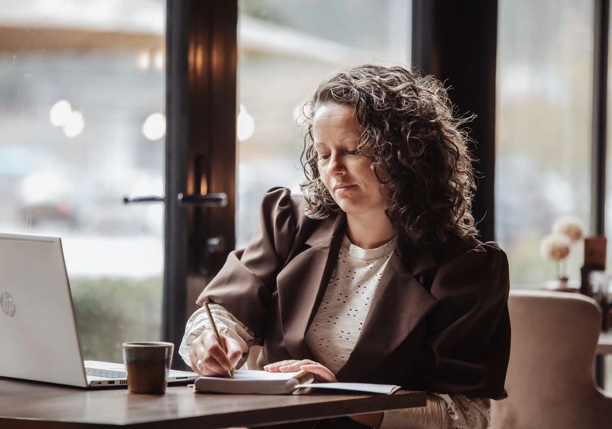 Georget schrijft aantekeningen naast haar laptop