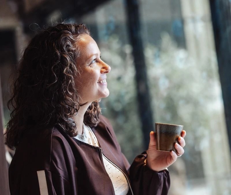 Georget kijkt naar buiten met een kop koffie in haar hand