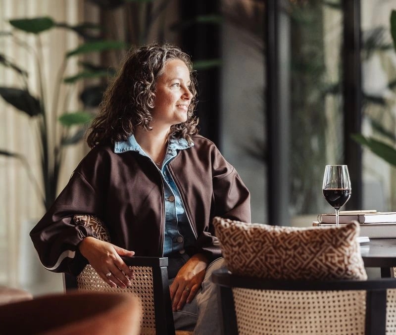 Georget zit met een glas wijn in een rieten stoel
